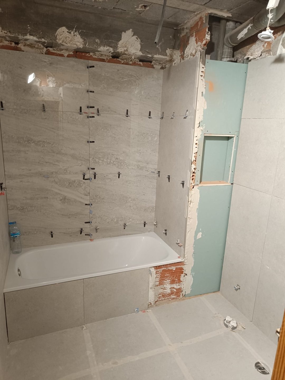 Tiling under way with levelling spacers over the bath