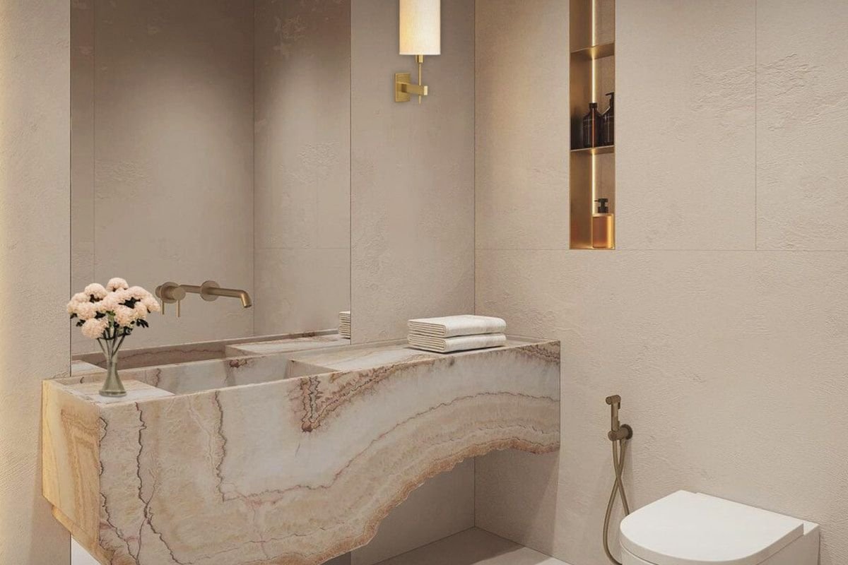 Bañera de piedra natural veteada empotrada en un baño de tonos travertino