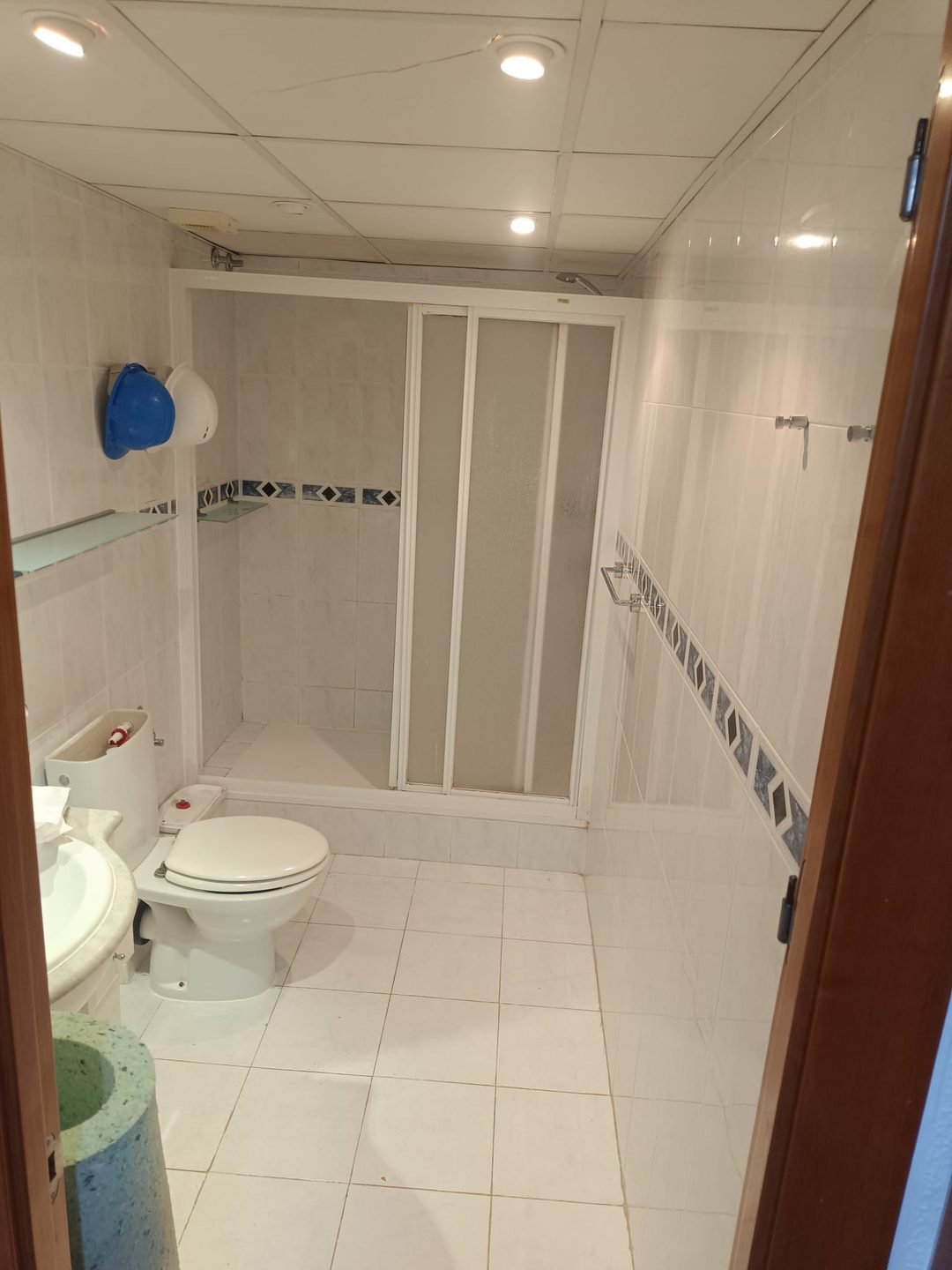Baño antiguo con plato de obra con escalón, mampara plegable de aluminio y alicatado con cenefa