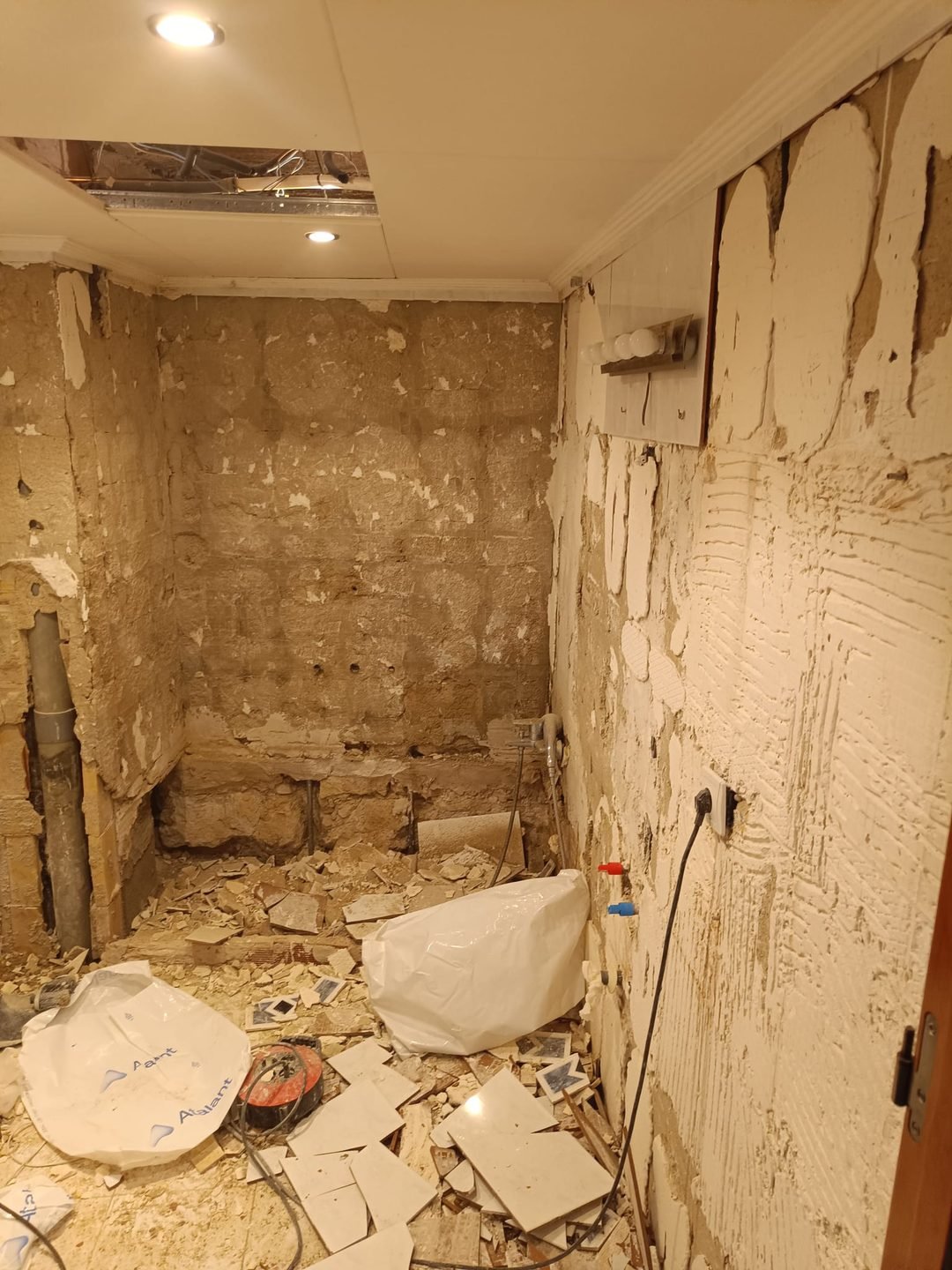 Baño en obra con los paramentos picados hasta el ladrillo y el escombro recogido