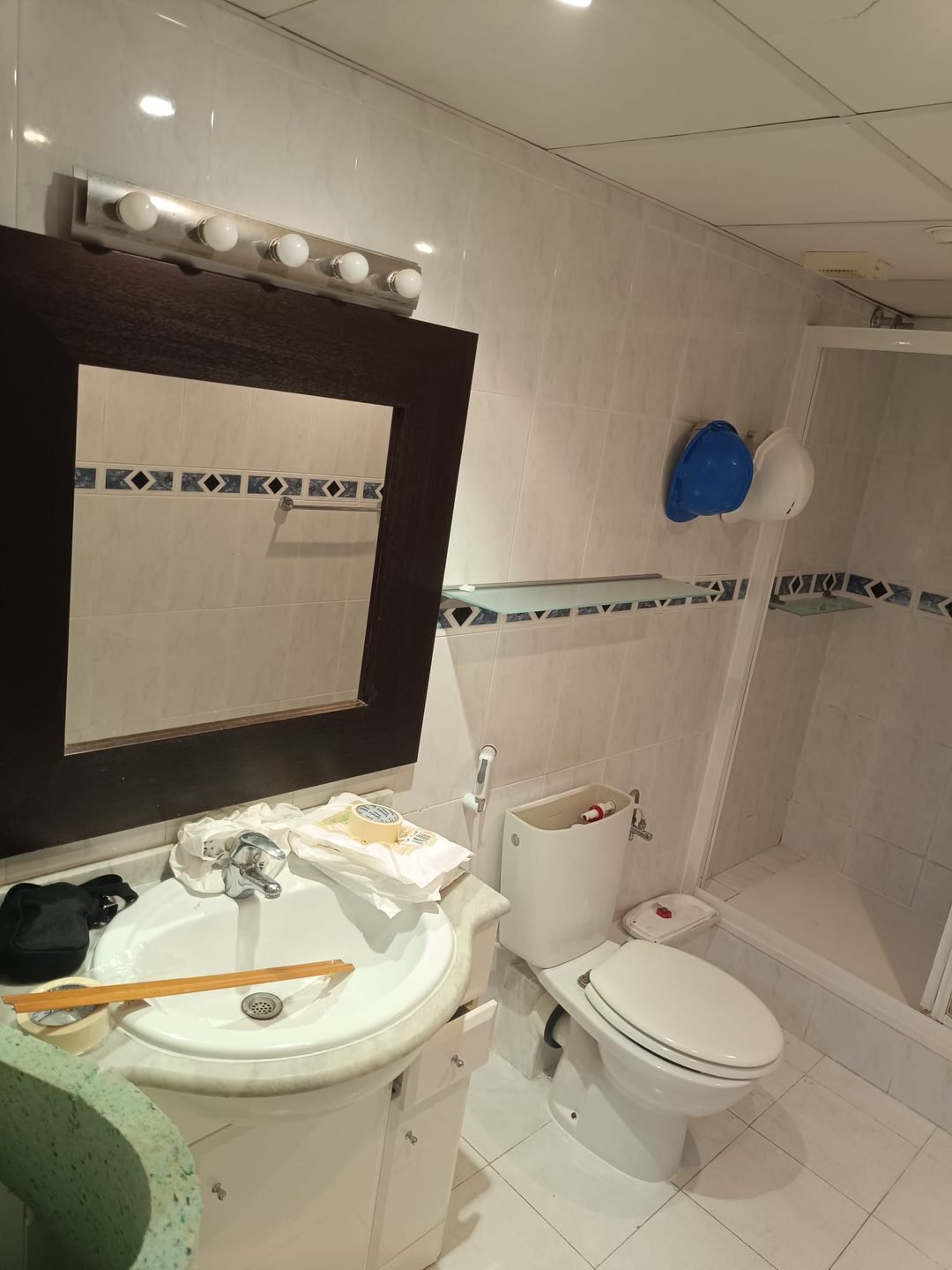 Lavabo antiguo con mueble bajo, espejo de marco oscuro y regleta de bombillas