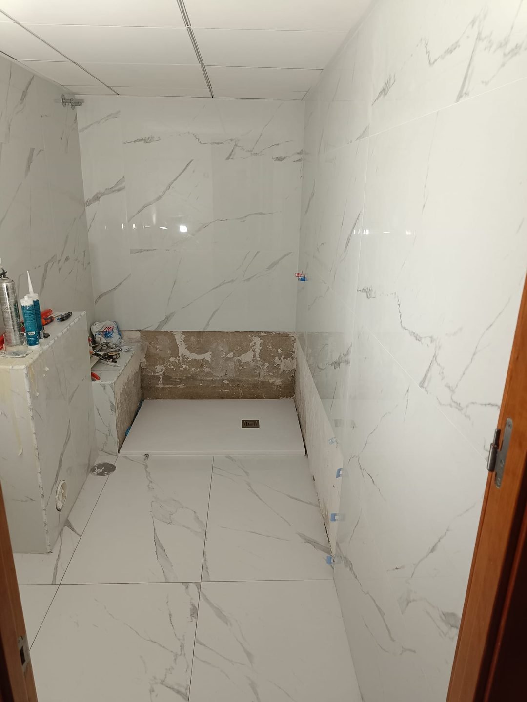 El baño ya revestido, con el plato de obra ejecutado y pendiente de acabados