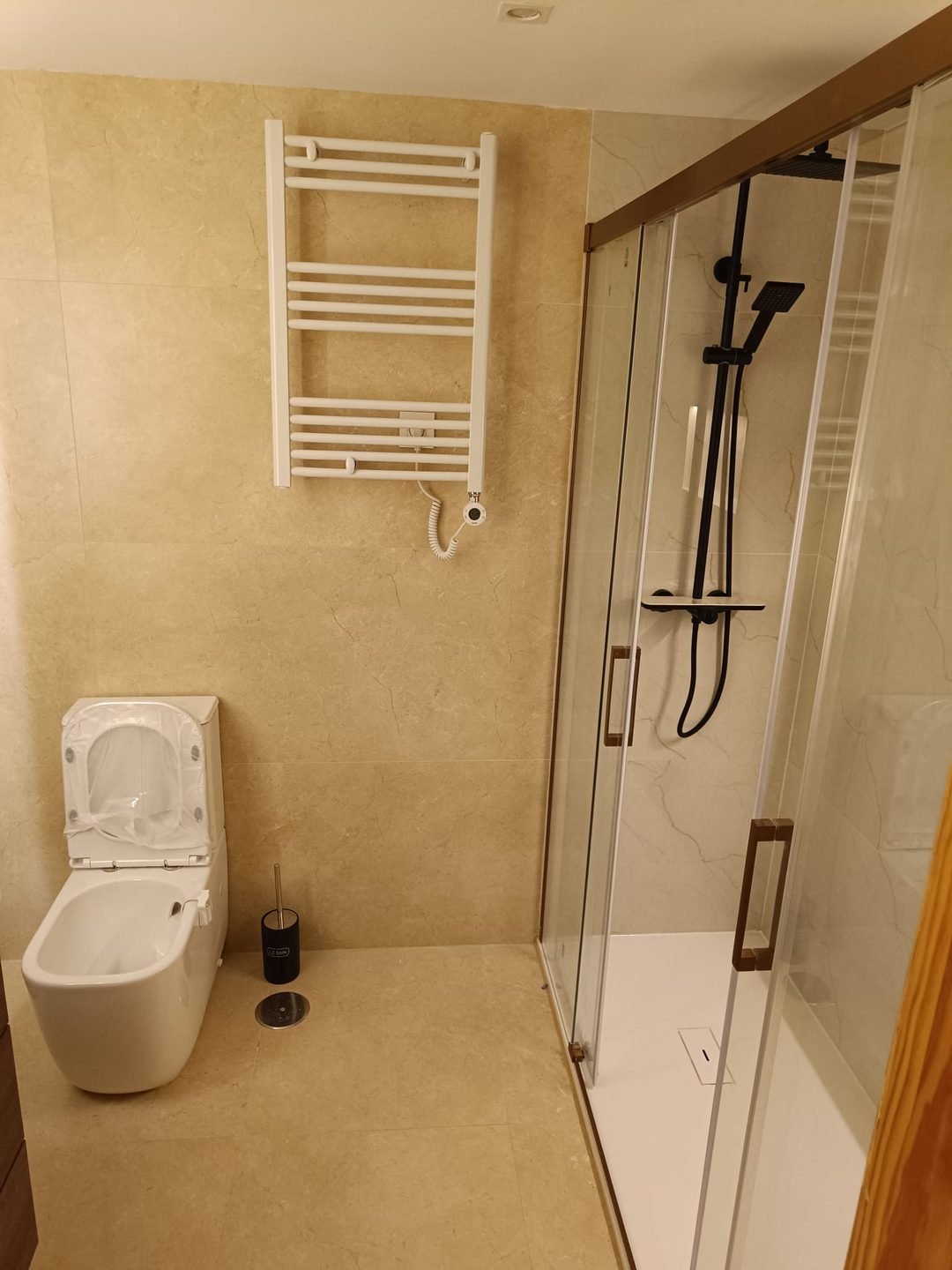 El mismo baño con plato de ducha, mampara corredera de tiradores bronce y bidé nuevo