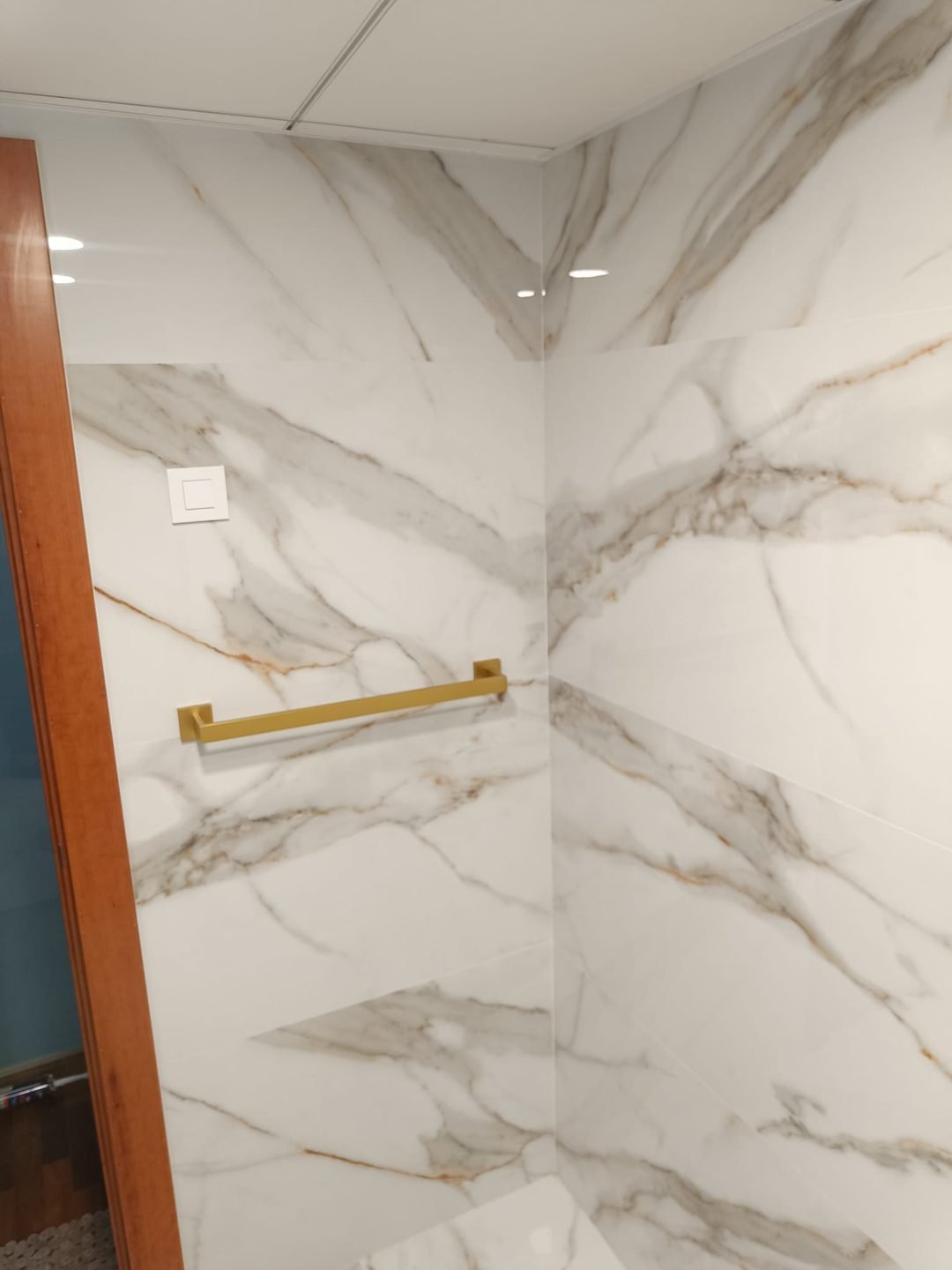 Close-up of the gold-veined porcelain with a gold towel rail on the wall