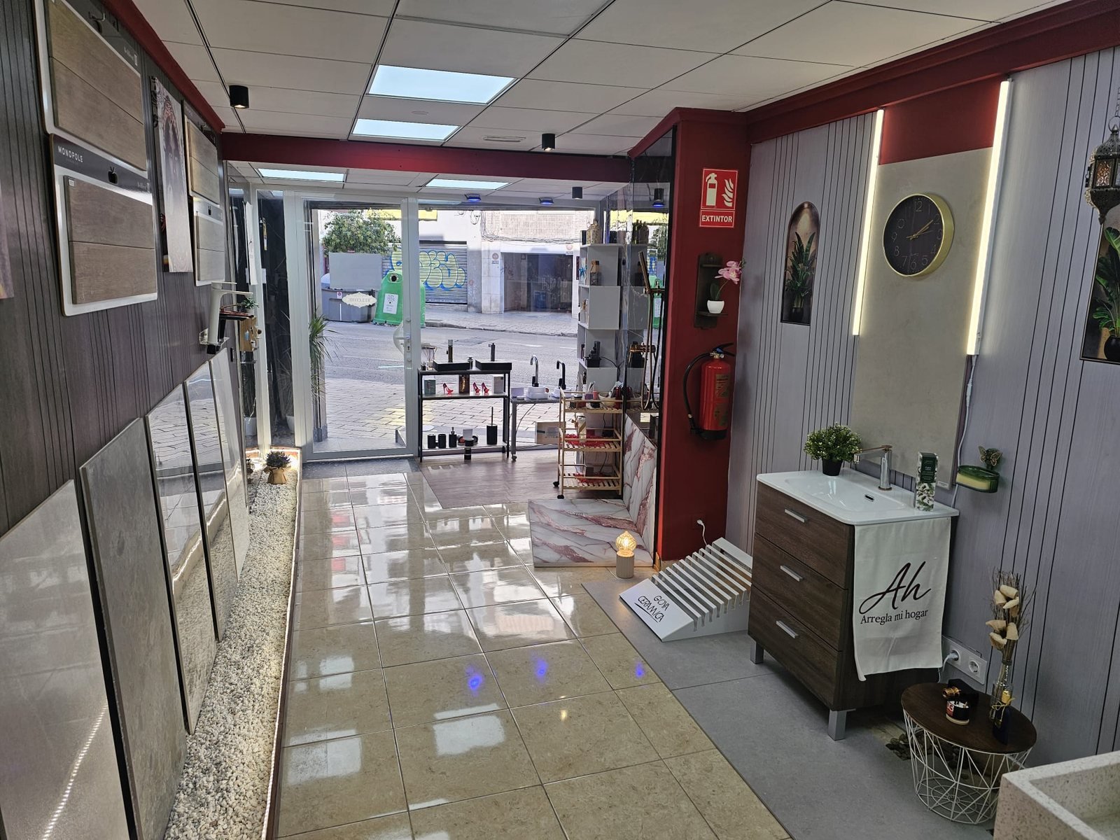 Exposición de Arregla mi hogar en Alicante: mueble de baño montado, muestras de porcelánico de gran formato y el escaparate al fondo