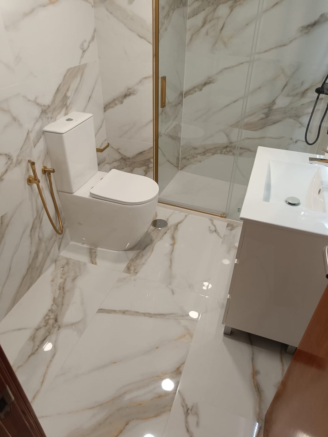 Veined porcelain floor with the WC and, at the back, the shower with the gold screen
