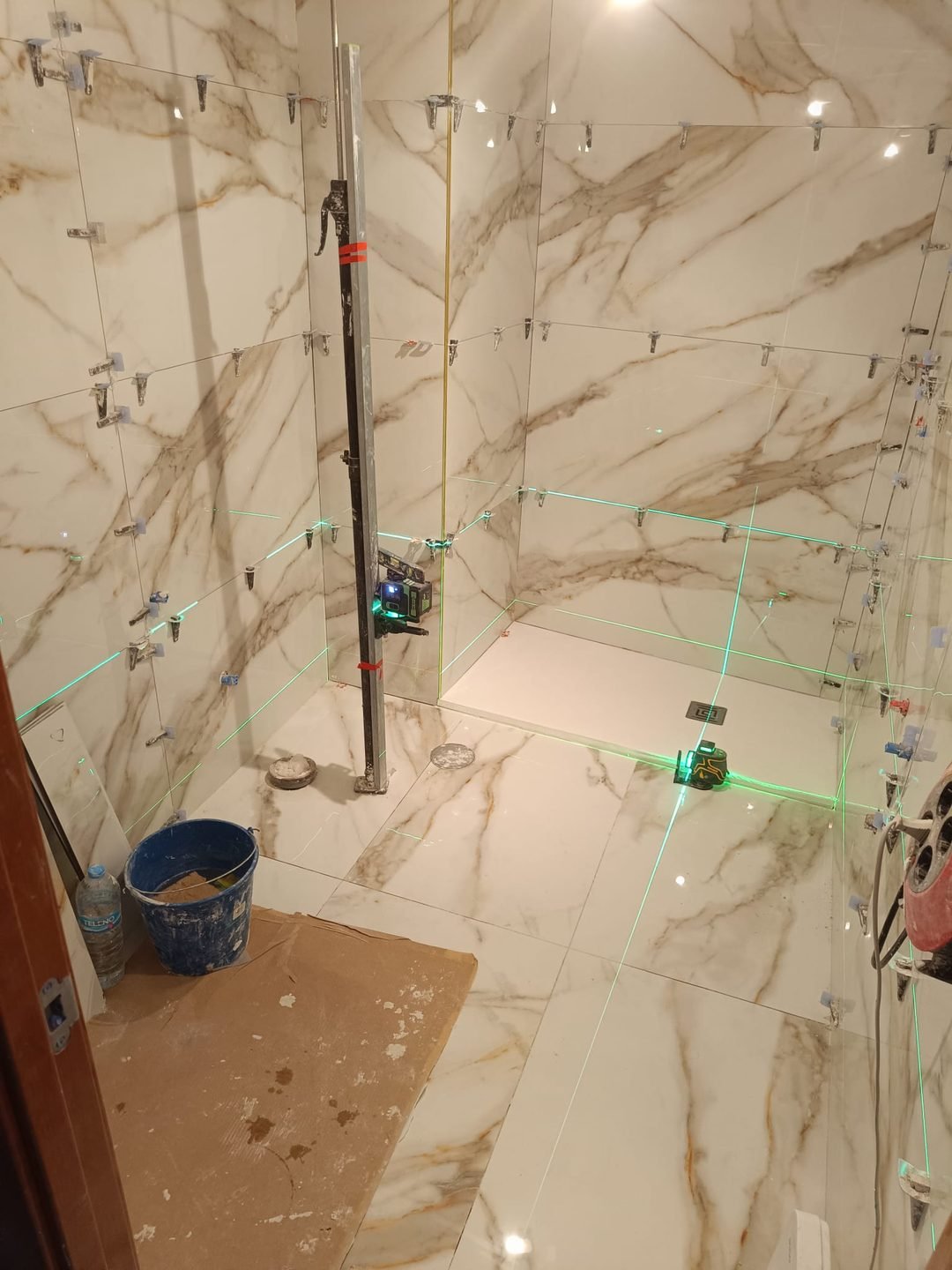 The shower area already clad, with the laser level setting out the screen